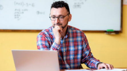 Man with glasses working at laptop.